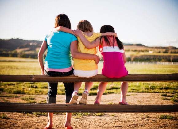 3 young girls sitting on fence
