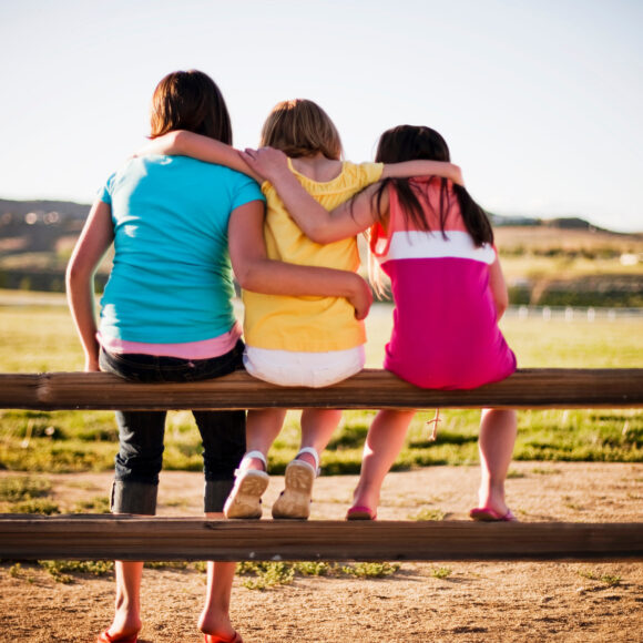 3 young girls sitting on fence