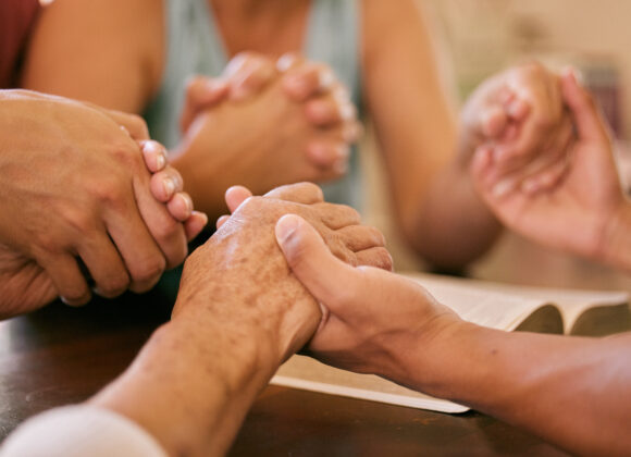 Christianity vs. Every Other Belief System Shot of a group of people holding hands in prayer.