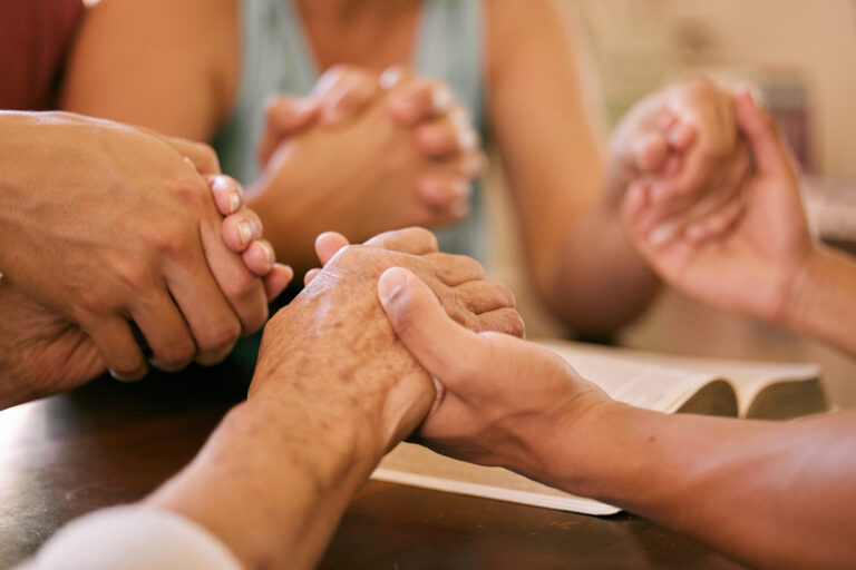 Christianity vs. Every Other Belief System Shot of a group of people holding hands in prayer.